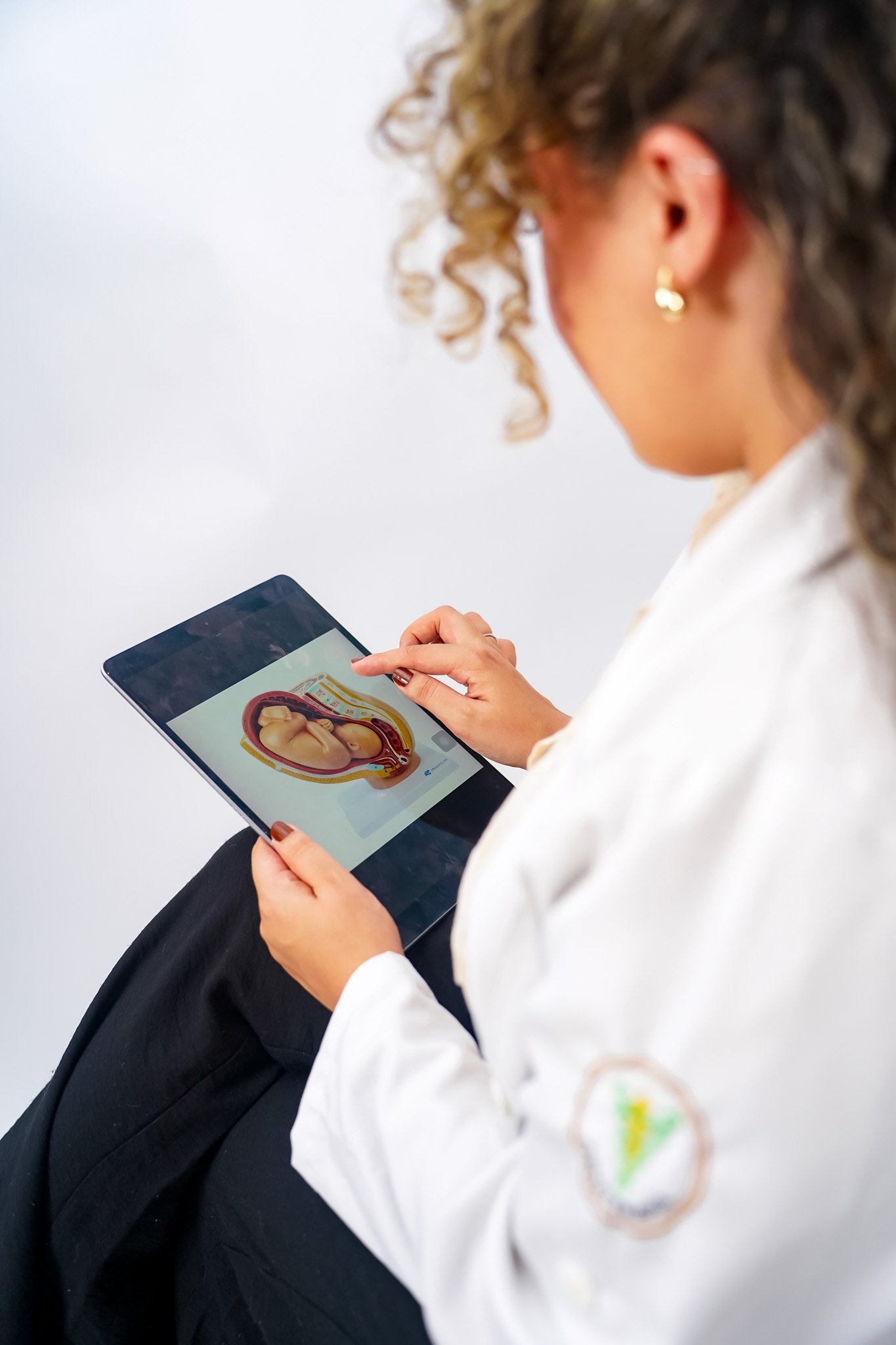 Mulher Fisioterapeuta segurando um tablet com uma representação de um feto